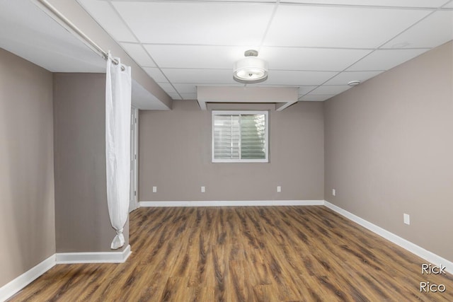 spare room with baseboards, wood finished floors, and a paneled ceiling