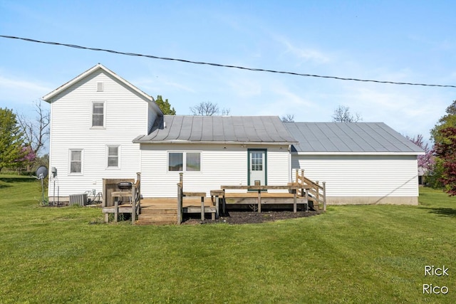 rear view of property featuring a standing seam roof, a lawn, central AC, a wooden deck, and metal roof