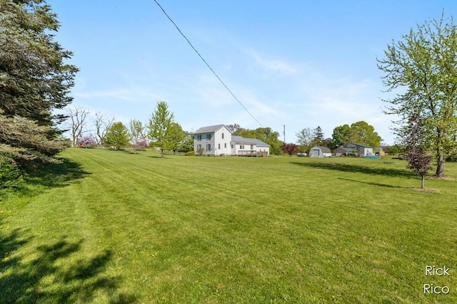 view of green lawn featuring an outbuilding and a storage shed