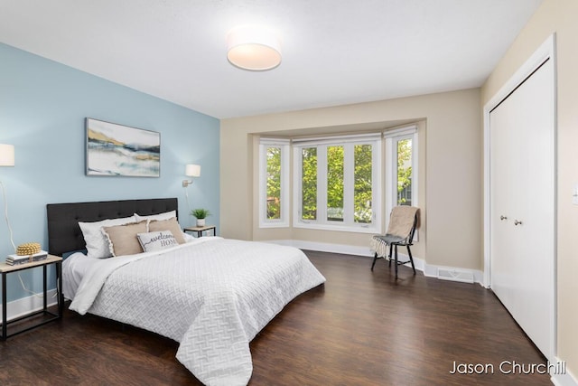 bedroom featuring dark wood finished floors, baseboards, and a closet