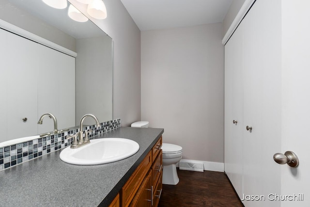 bathroom featuring vanity, toilet, baseboards, and wood finished floors