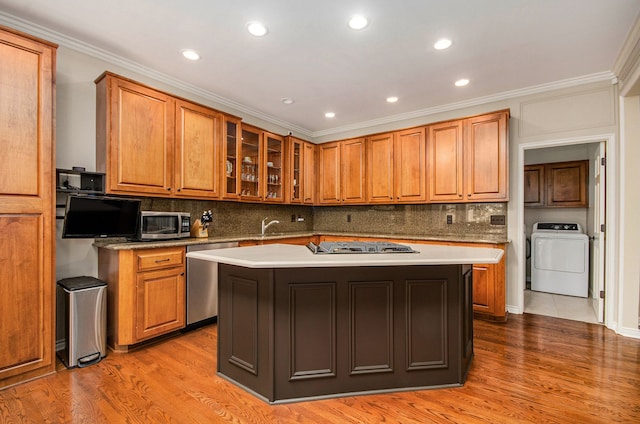2200 Clearwood, Shelby Twp, MI 48316 - kitchen featuring washer / clothes dryer, stainless steel appliances, wood finished floors, brown cabinets, and ornamental molding
