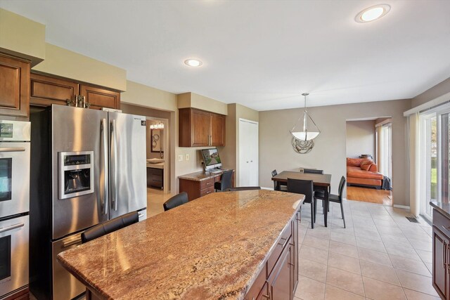 7039 Timberview Trl, West Bloomfield, MI 48322 - kitchen featuring appliances with stainless steel finishes, a center island, light tile patterned floors, hanging light fixtures, and light stone countertops