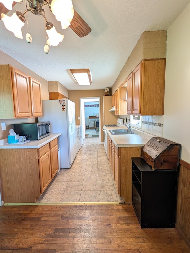 5062 Kendall Dr, Burton, MI 48509 - kitchen featuring white appliances, light countertops, light wood-type flooring, a sink, and a textured ceiling