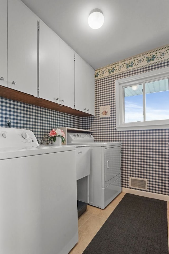 laundry room featuring washer and dryer, cabinet space, wallpapered walls, and light tile patterned flooring