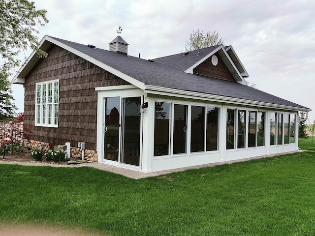 back of house with a sunroom, a yard, and a shingled roof