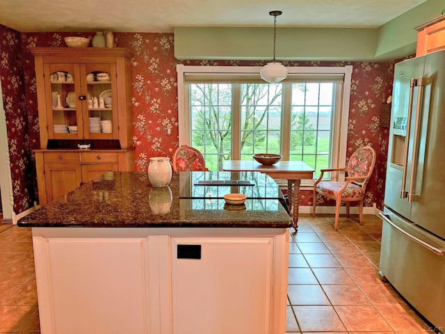 kitchen featuring high end fridge, wallpapered walls, light tile patterned flooring, and plenty of natural light