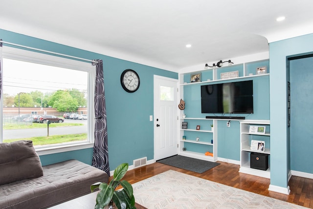 living area featuring wood finished floors, baseboards, built in shelves, and recessed lighting