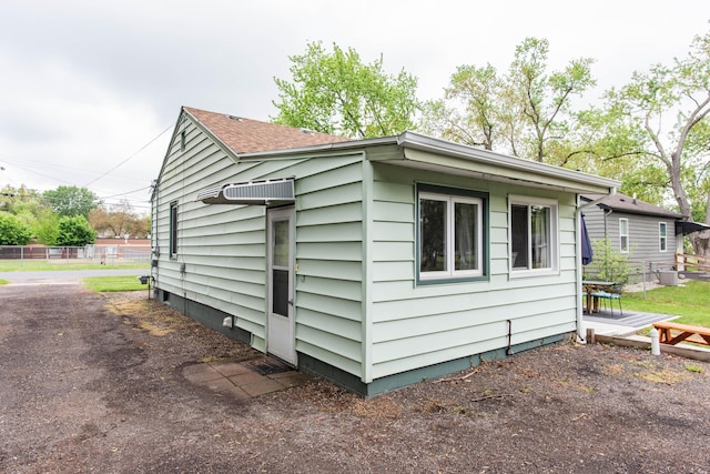 view of side of property featuring a shingled roof, a wooden deck, and fence