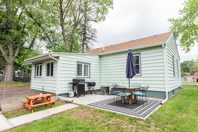 rear view of property with a patio, central air condition unit, and roof with shingles