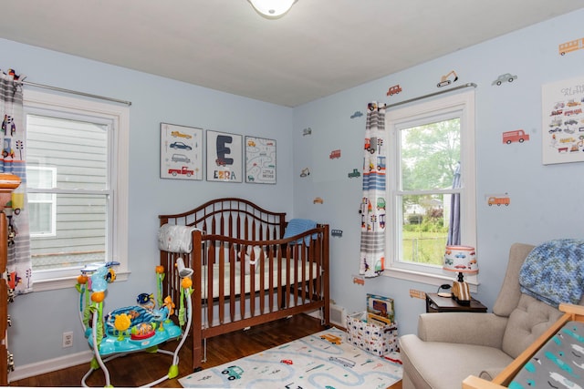 bedroom with a nursery area, wood finished floors, and baseboards