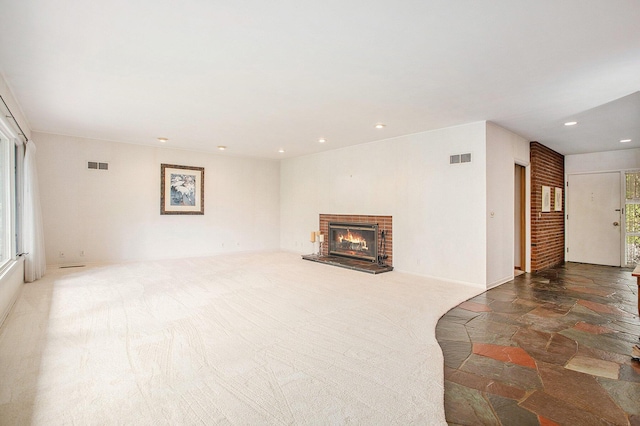unfurnished living room with a fireplace, recessed lighting, and stone finish flooring