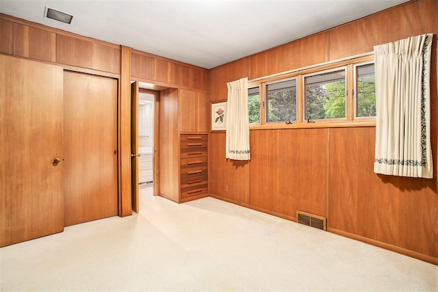 unfurnished bedroom featuring a closet, wood walls, and carpet flooring