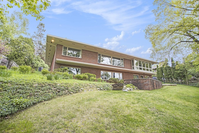 back of property with brick siding and a yard