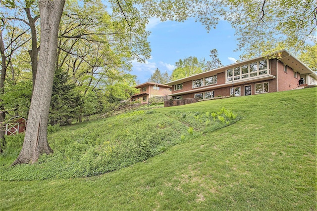rear view of property featuring brick siding and a lawn