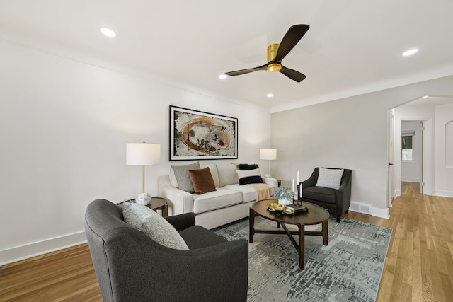 living area with a ceiling fan, light wood-style floors, arched walkways, recessed lighting, and baseboards