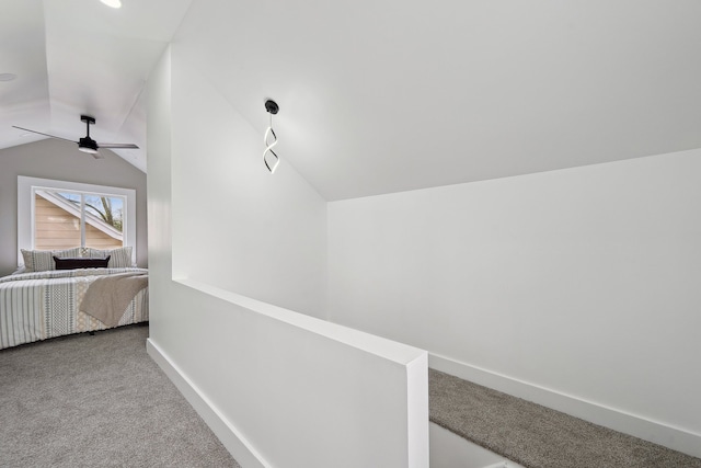 corridor with carpet flooring, vaulted ceiling, and baseboards
