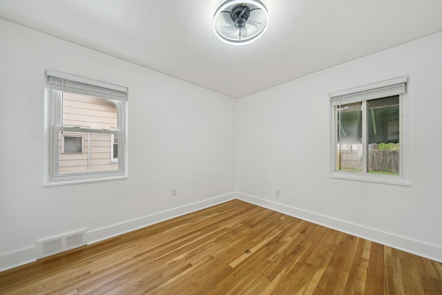 spare room featuring crown molding, light wood-style flooring, and baseboards