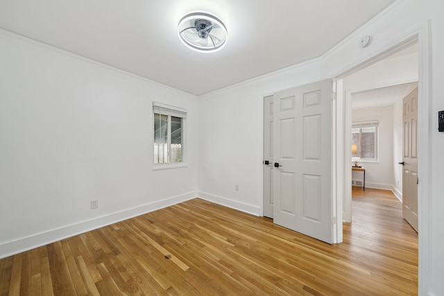unfurnished bedroom featuring light wood finished floors, multiple windows, baseboards, and crown molding