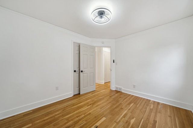 spare room with baseboards, light wood-type flooring, and crown molding