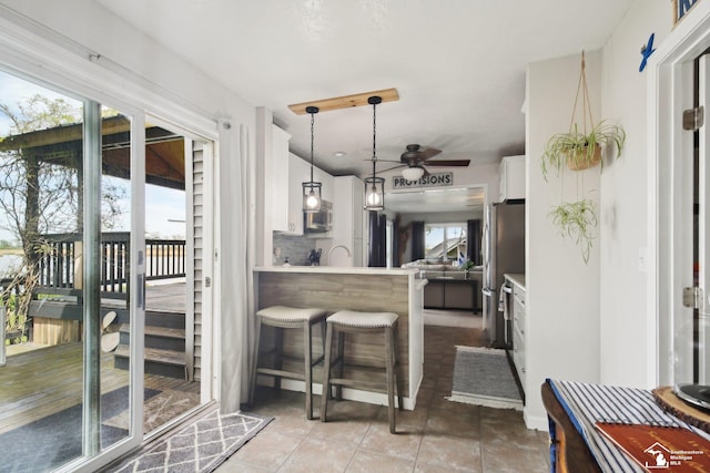 3131 Morin Point St, Erie, MI 48133 - kitchen with a ceiling fan, white cabinetry, stainless steel microwave, a breakfast bar, and hanging light fixtures