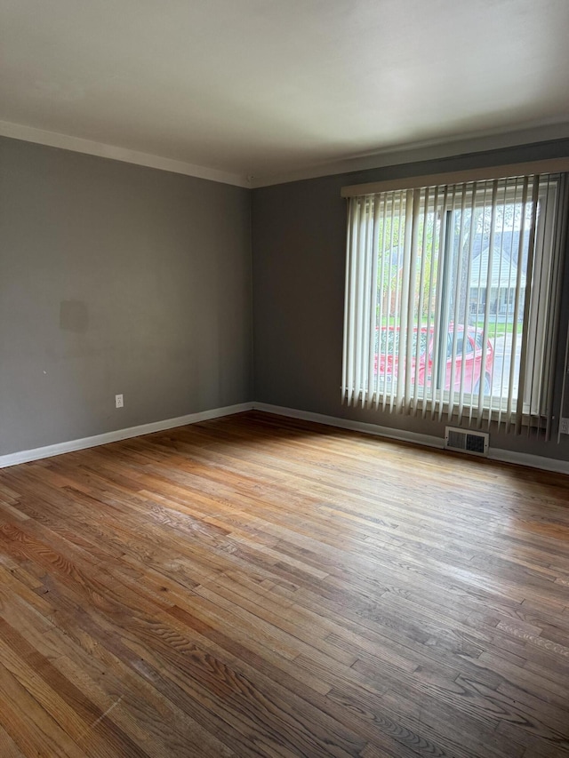 spare room featuring ornamental molding, wood finished floors, and baseboards