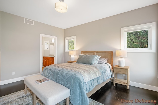 bedroom with baseboards, dark wood finished floors, and ensuite bath