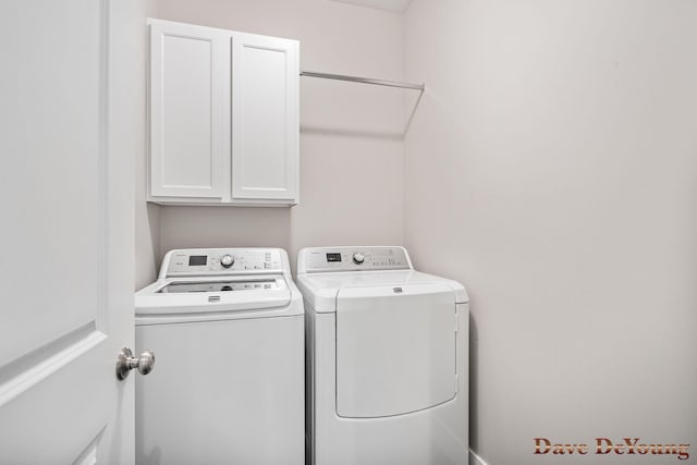 clothes washing area featuring separate washer and dryer and cabinet space