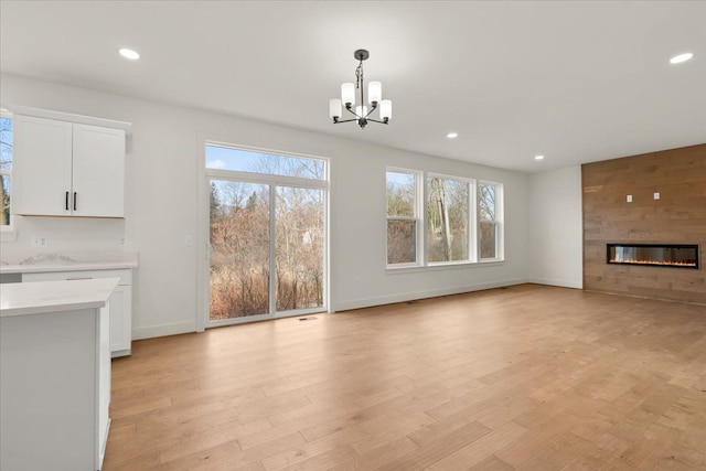 6515 Cambridge Cir, Clarkston, MI 48346 - unfurnished living room featuring a chandelier, baseboards, healthy amount of natural light, recessed lighting, and light wood-type flooring
