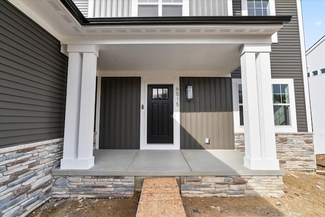 6515 Cambridge Cir, Clarkston, MI 48346 - view of exterior entry featuring stone siding, covered porch, and board and batten siding