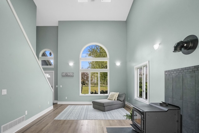 19101 Weller Rd, Gregory, MI 48137 - living area featuring a high ceiling, wood finished floors, baseboards, and a wood stove