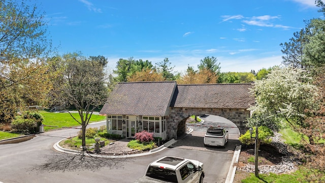 view of front of house featuring driveway, stone siding, and a sunroom