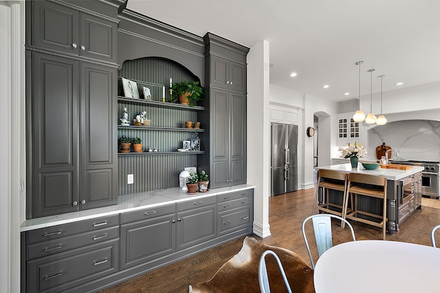 bar area with high end appliances, arched walkways, dark wood finished floors, hanging light fixtures, and recessed lighting