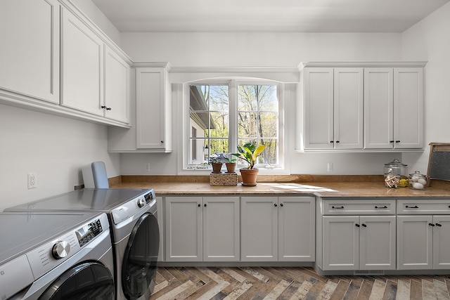 clothes washing area featuring washing machine and clothes dryer and cabinet space