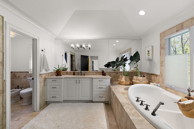 bathroom featuring vaulted ceiling, a garden tub, vanity, toilet, and ornamental molding