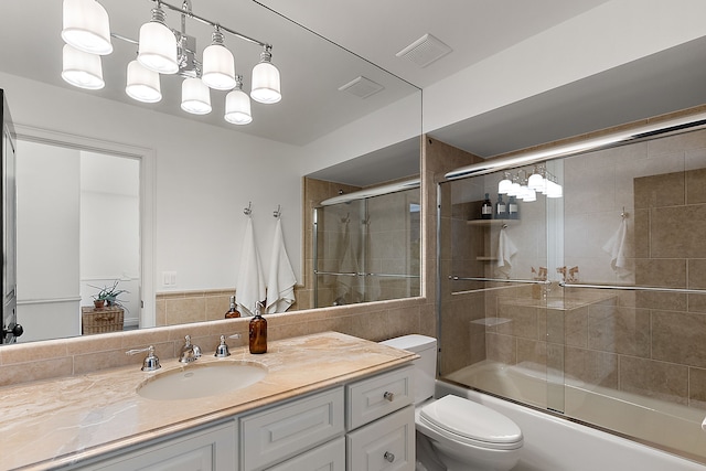 bathroom featuring vanity, toilet, and shower / bath combination with glass door