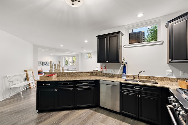 kitchen featuring appliances with stainless steel finishes, a sink, dark cabinetry, a peninsula, and recessed lighting