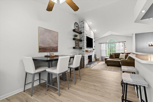 2694 Driftwood Dr, Waterford, MI 48329 - dining space featuring vaulted ceiling, a stone fireplace, wood finished floors, a ceiling fan, and baseboards