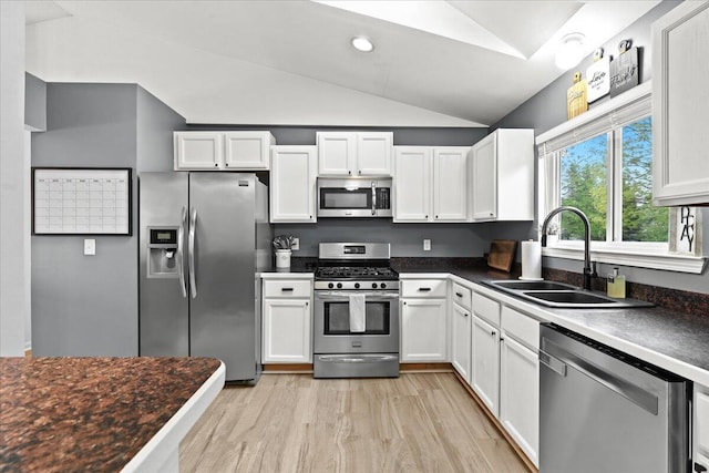 2694 Driftwood Dr, Waterford, MI 48329 - kitchen with appliances with stainless steel finishes, vaulted ceiling, a sink, white cabinetry, and dark countertops