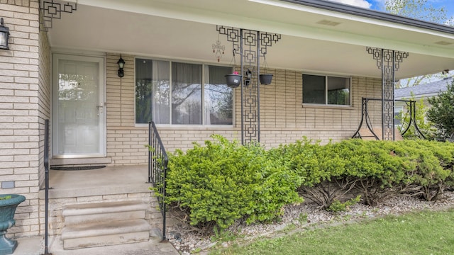 entrance to property with brick siding and covered porch