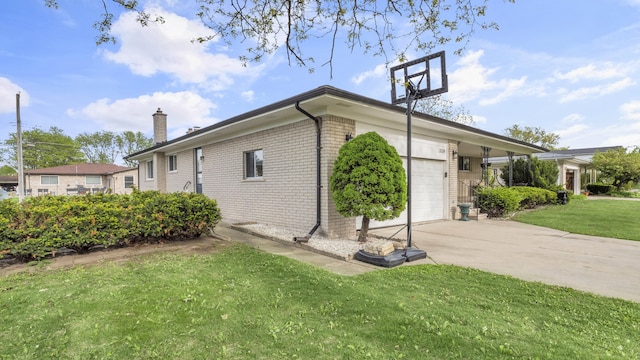 view of side of property with brick siding, a chimney, driveway, an attached garage, and a yard