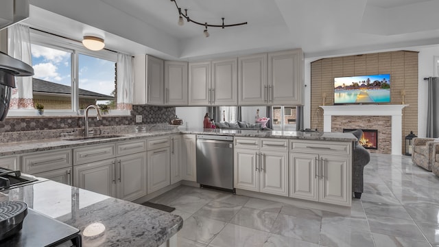 kitchen featuring dishwasher, a sink, a tray ceiling, track lighting, and a fireplace