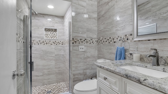 full bathroom with toilet, a stall shower, vanity, and tile walls