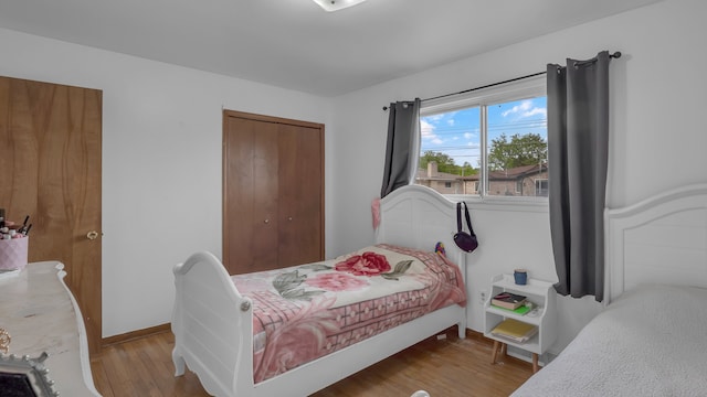 bedroom with a closet, wood finished floors, and baseboards