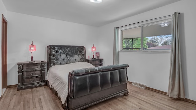 bedroom featuring light wood finished floors and baseboards