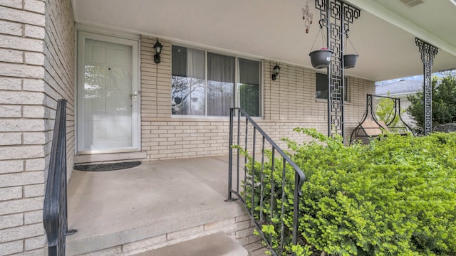 property entrance featuring a porch and brick siding