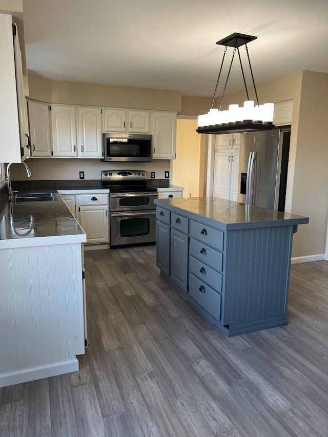 9220 Cotters Ridge Rd, Richland, MI 49083 - kitchen featuring appliances with stainless steel finishes, a sink, white cabinets, dark wood-style floors, and a center island