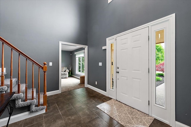 foyer with a high ceiling, stairs, and baseboards