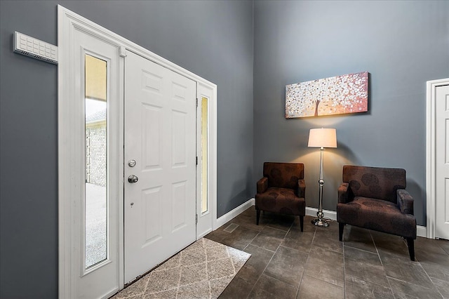 foyer entrance featuring baseboards, plenty of natural light, and dark stone finish floors