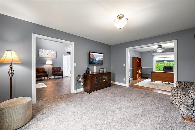 carpeted living area with baseboards and ceiling fan